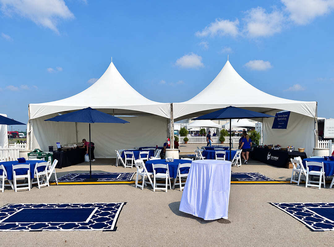 Sponsor hospitality area with white tents, shaded tables, and seating at the airshow.